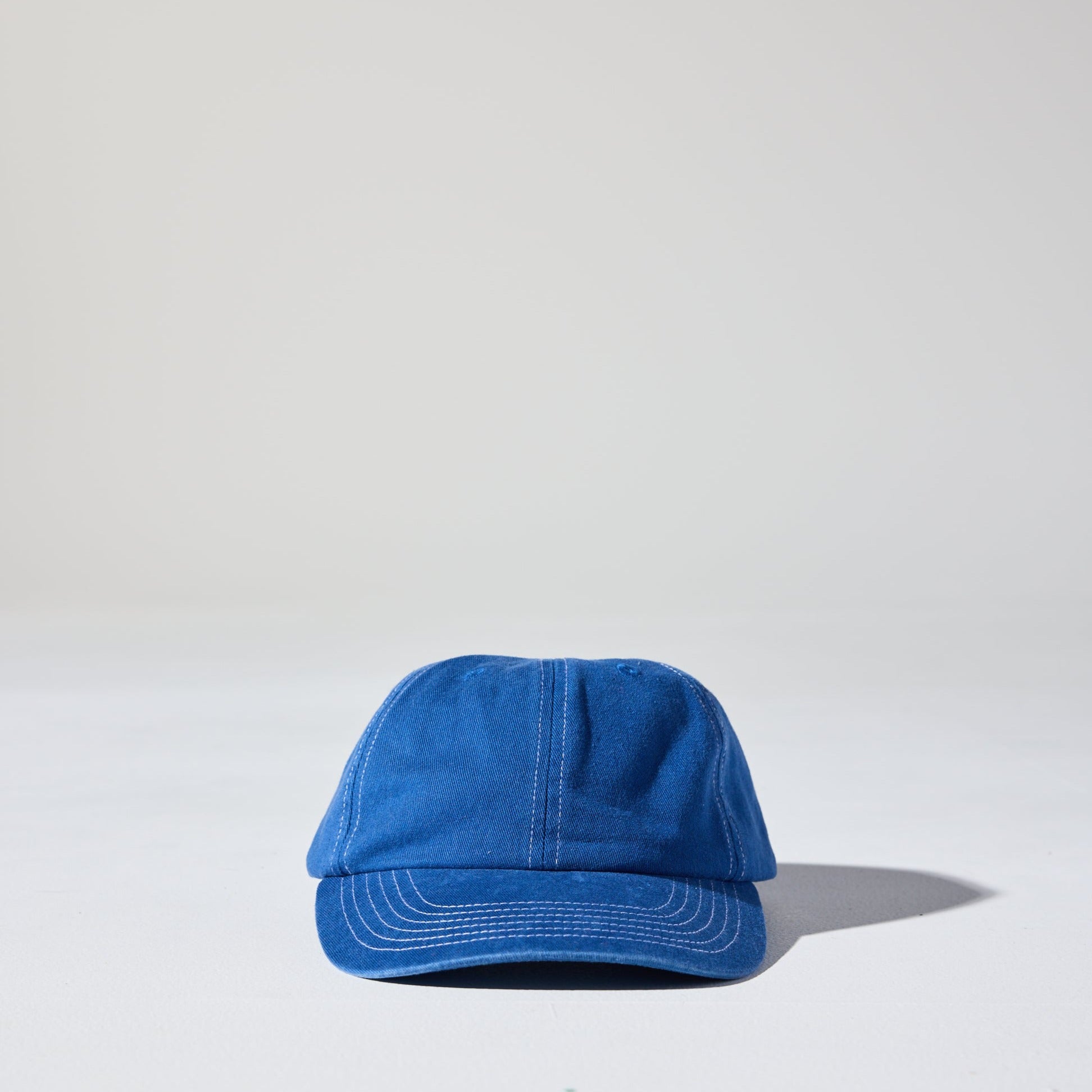 A blue 6 panel 'Dad' cap with white contrast stitching and an adjustable plastic fastener.
