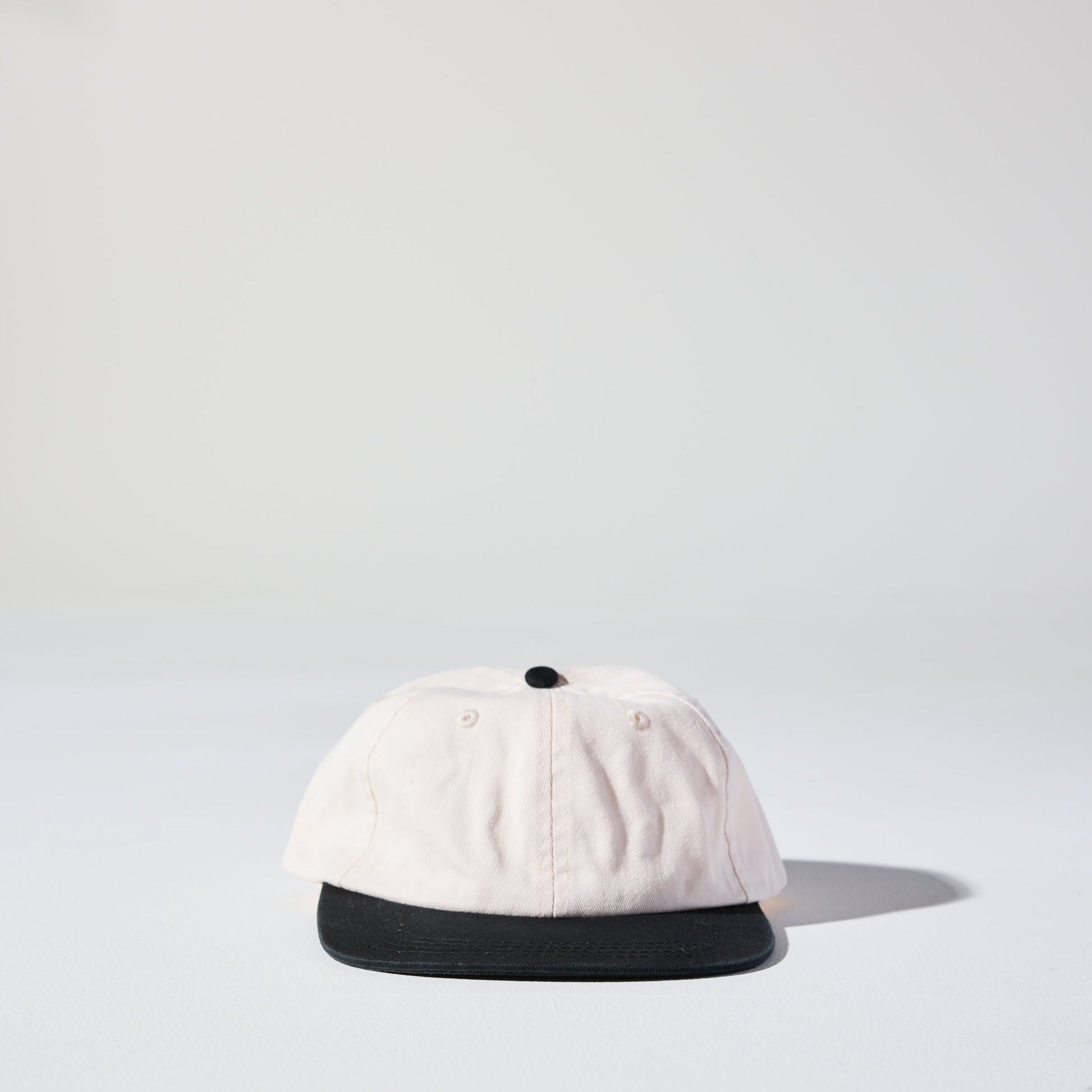 A beige and black two-tone 6 panel hard flat brim cap with an adjustable snap closure. This hat is a 90s Retro low profile Thursday Cap by House of Peaks.