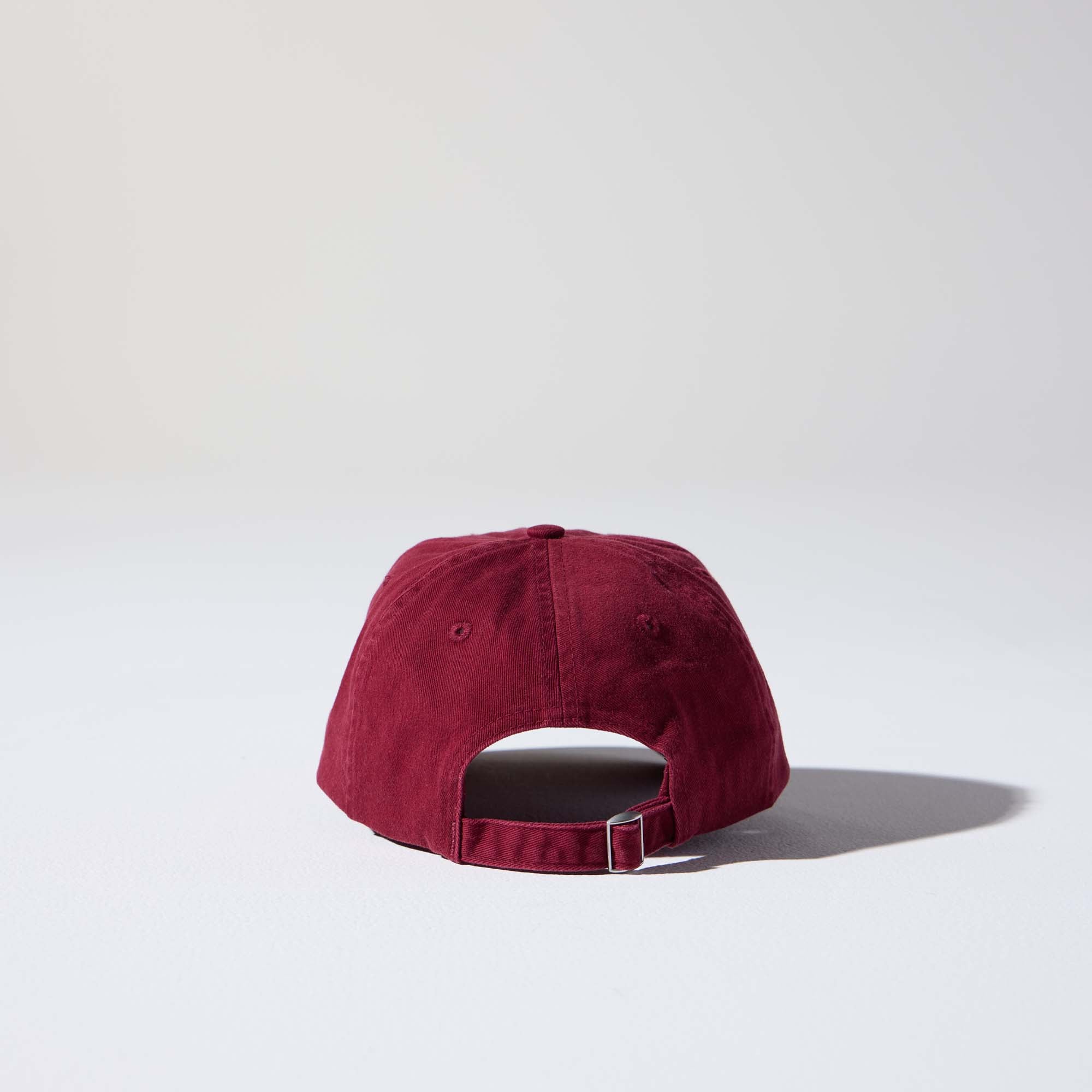 A burgundy-coloured, 6-panel unstructured 'Dad' cap made of recycled cotton twill with an adjustable material buckle. Best Blank Hats by House of Peaks.