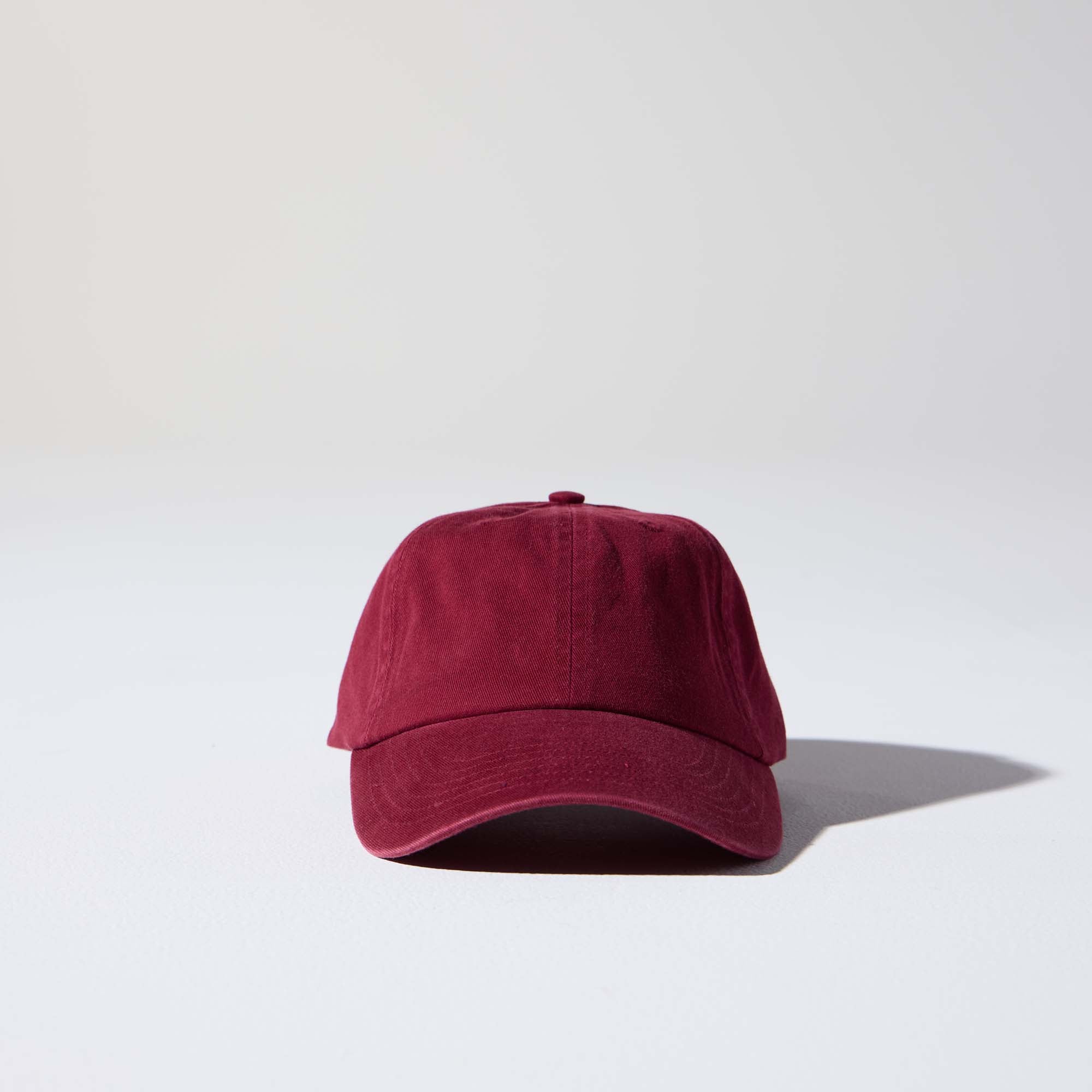 A burgundy-coloured, 6-panel unstructured 'Dad' cap made of recycled cotton twill with an adjustable material buckle. Best Blank Hats by House of Peaks.
