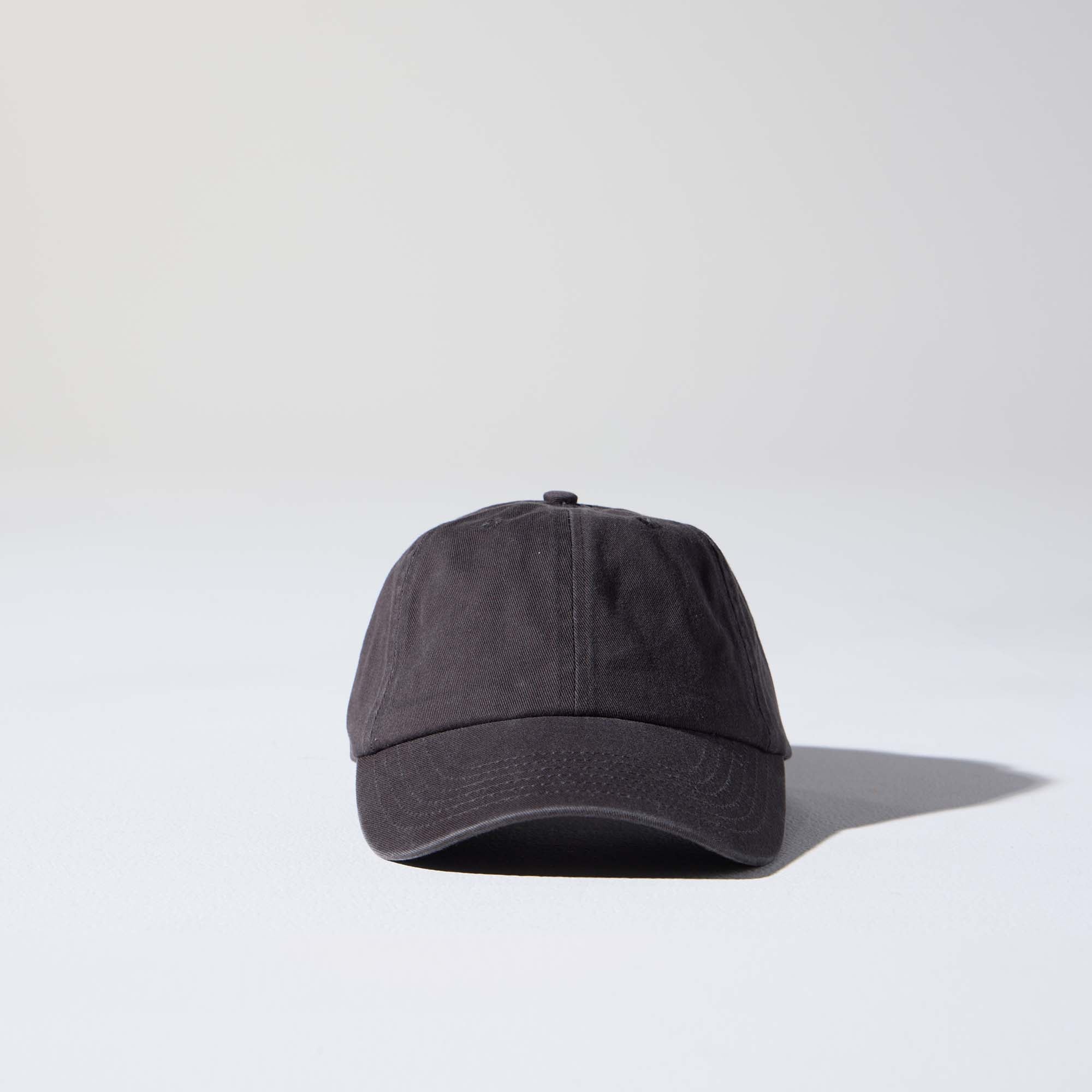 A dark charcoal-coloured, 6-panel unstructured 'Dad' cap made of recycled cotton twill with an adjustable material buckle. Best Blank Hats by House of Peaks.