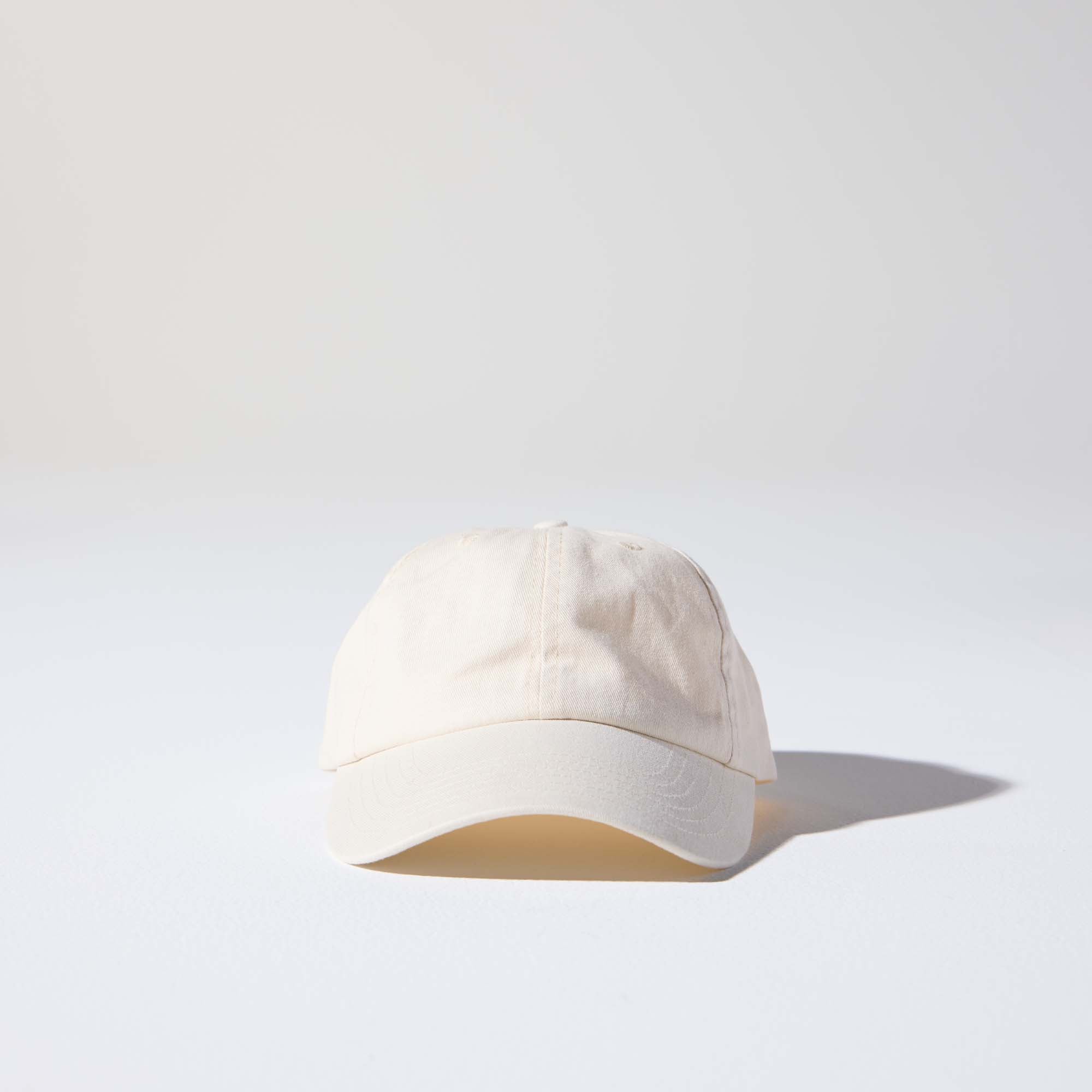 A creamy natural-coloured, 6-panel unstructured 'Dad' cap made of recycled cotton twill with an adjustable material buckle. Best Blank Hats by House of Peaks.