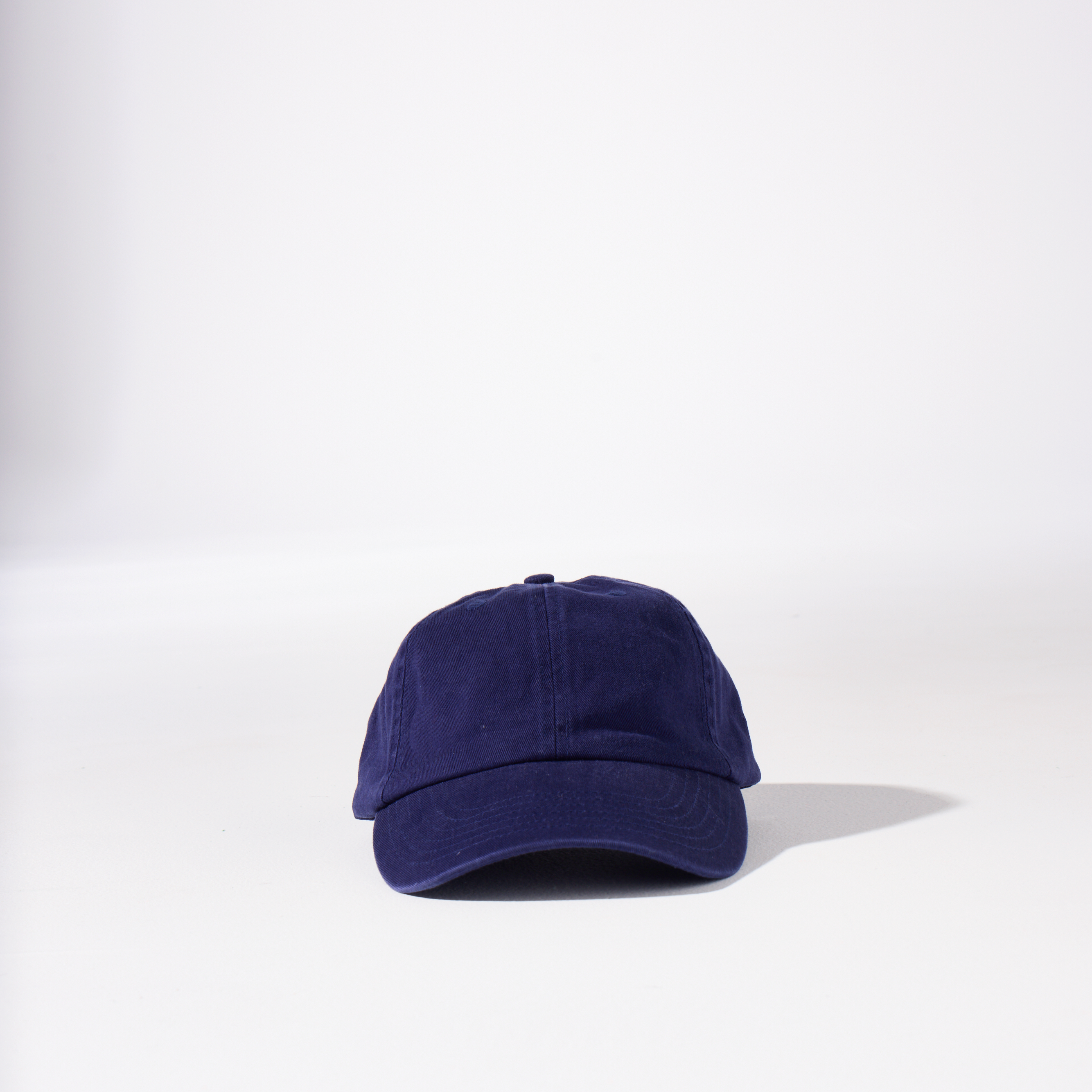 A navy-coloured, 6-panel unstructured 'Dad' cap made of recycled cotton twill with an adjustable material buckle. Best Blank Hats by House of Peaks.