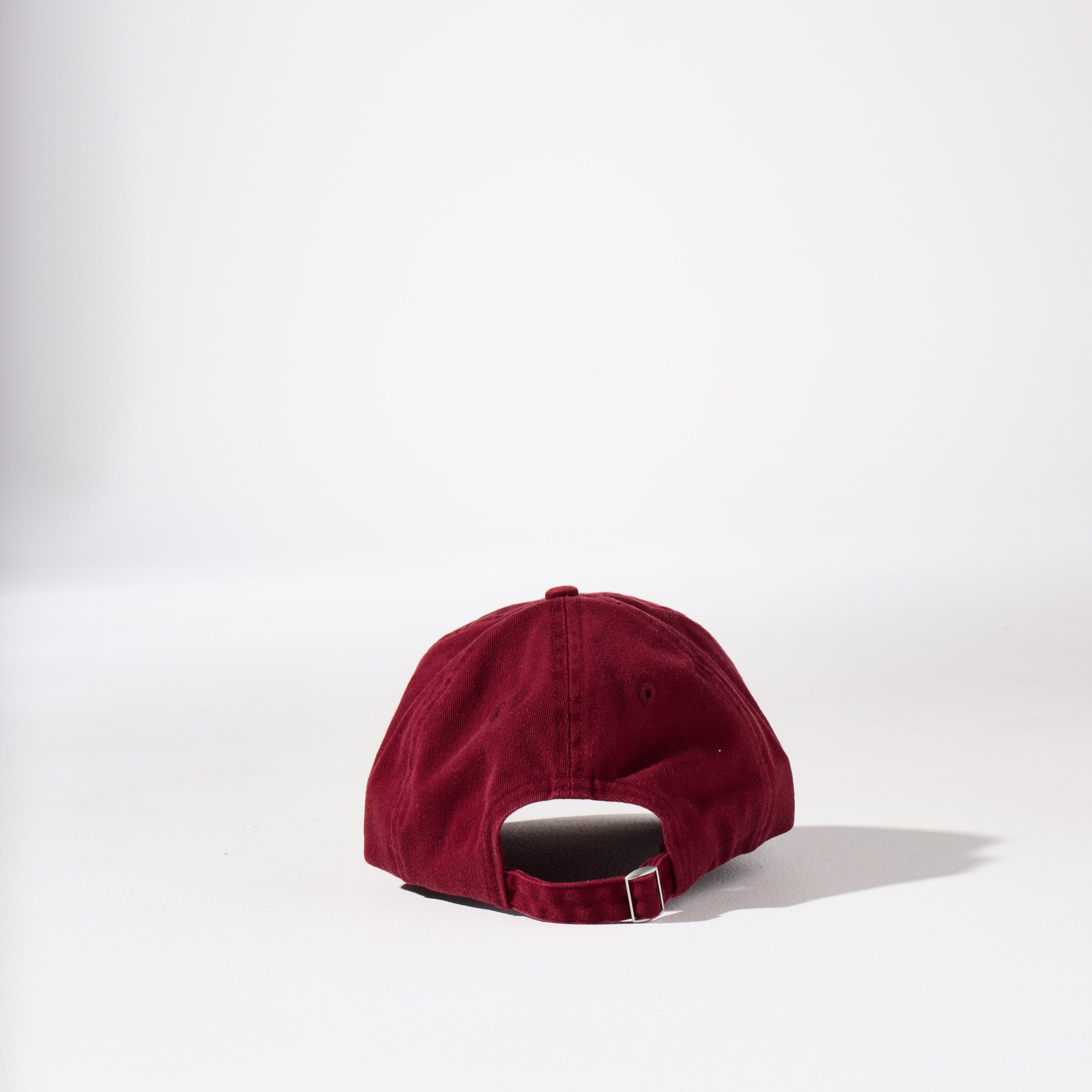 A burgundy-coloured, 6-panel unstructured 'Dad' cap made of recycled cotton twill with an adjustable material buckle. Best Blank Hats by House of Peaks.
