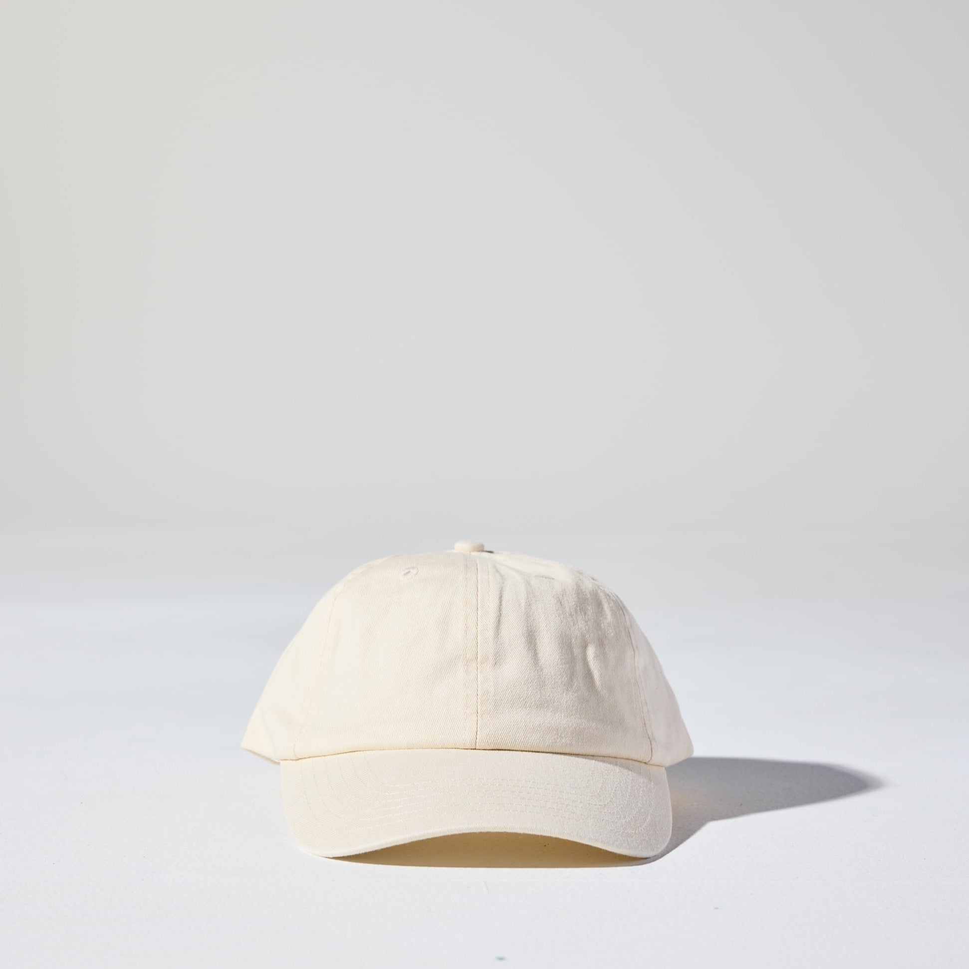 A cream coloured, 6-panel unstructured 'Dad' baseball cap made of recycled cotton twill with snap back by House of Peaks.