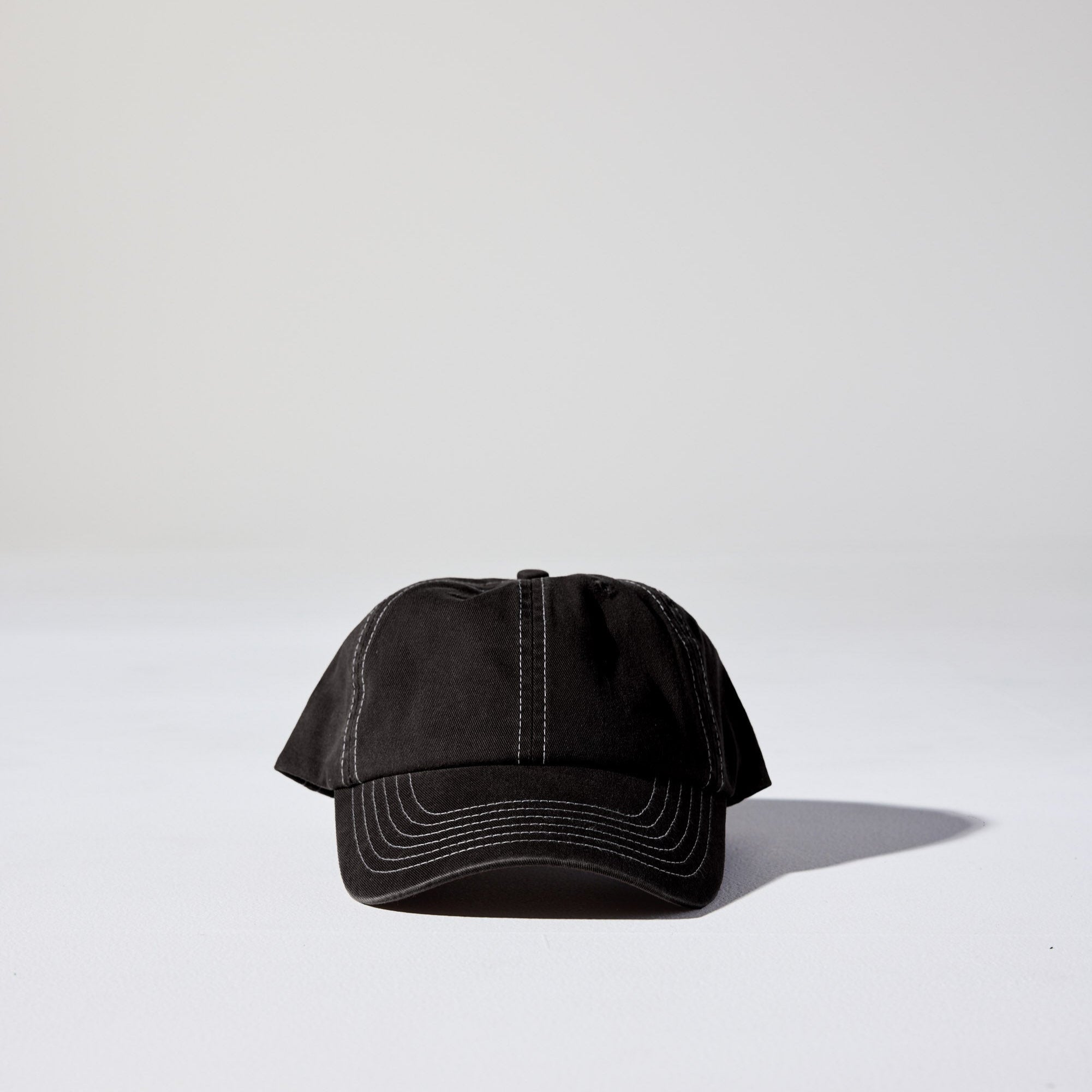A black 6 panel 'Dad' cap with white contrast stitching and an adjustable plastic snapback fastener. Best Blank Hats by House of Peaks.