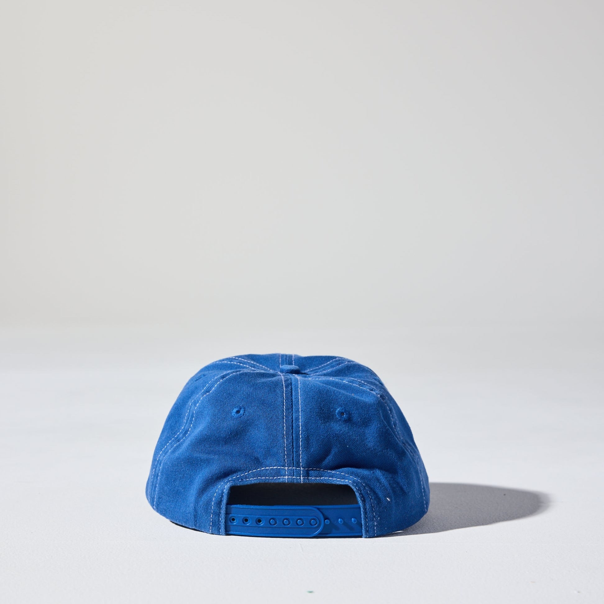 A washed blue 6 panel 'Dad' cap with white contrast stitching and an adjustable plastic snapback adjustment. Best Blank Hats by House of Peaks.