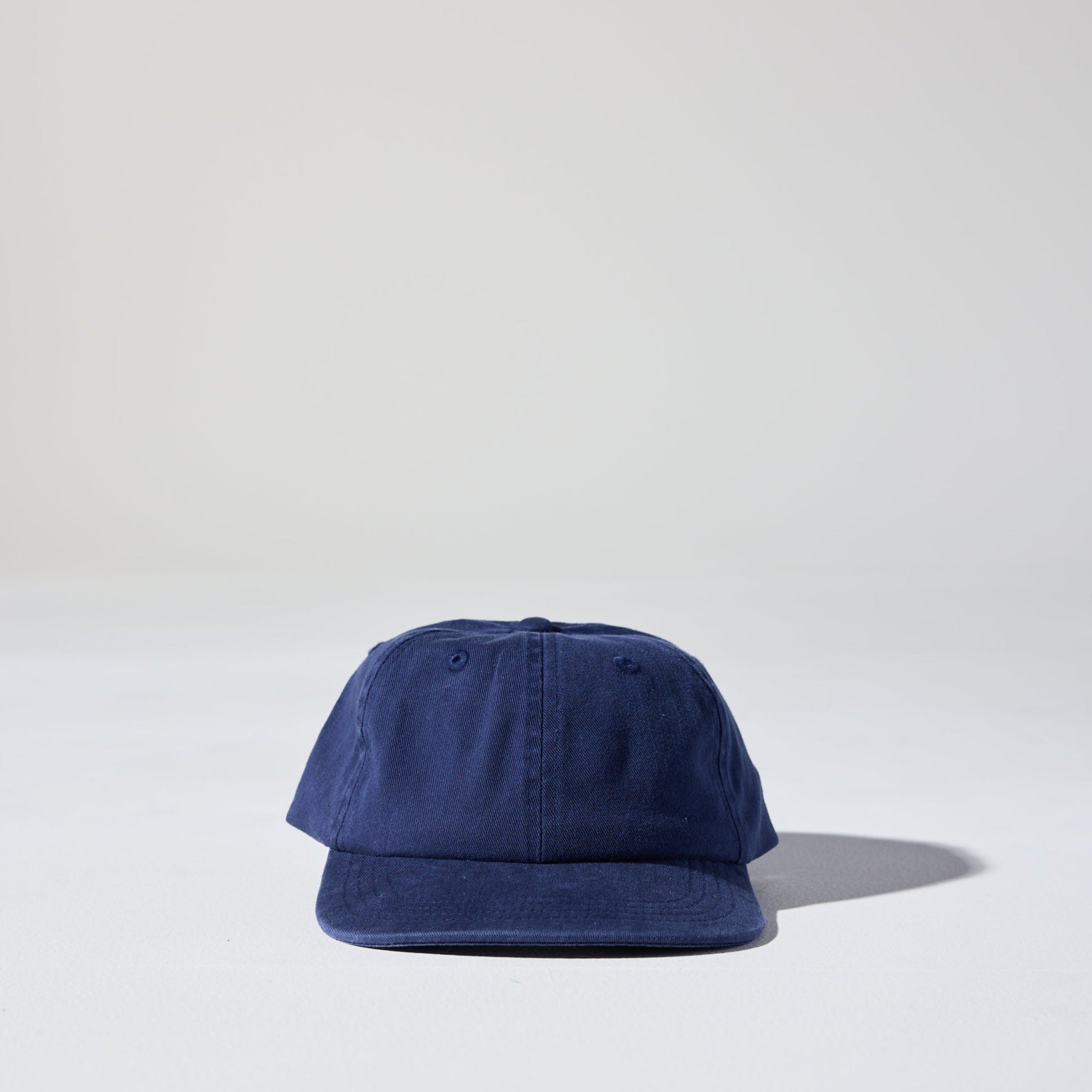 A retro style faded navy blue Monday Buckle Cap by House of Peaks with an adjustable strap, placed against a white background.