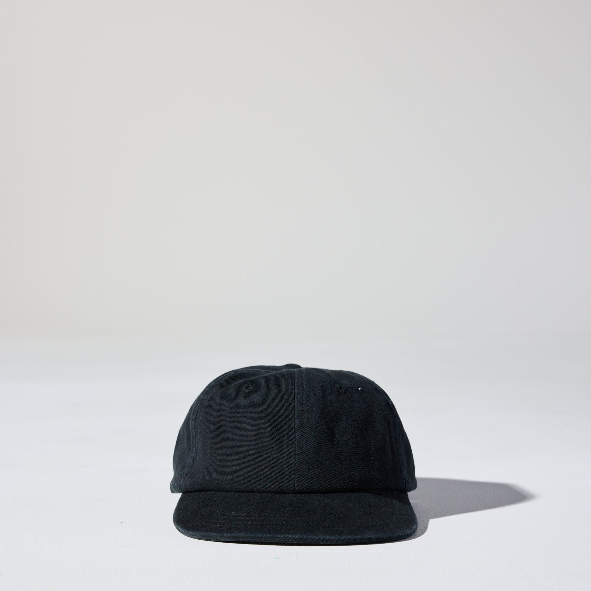 A black Monday Buckle Cap with an adjustable strap, placed against a white background.
