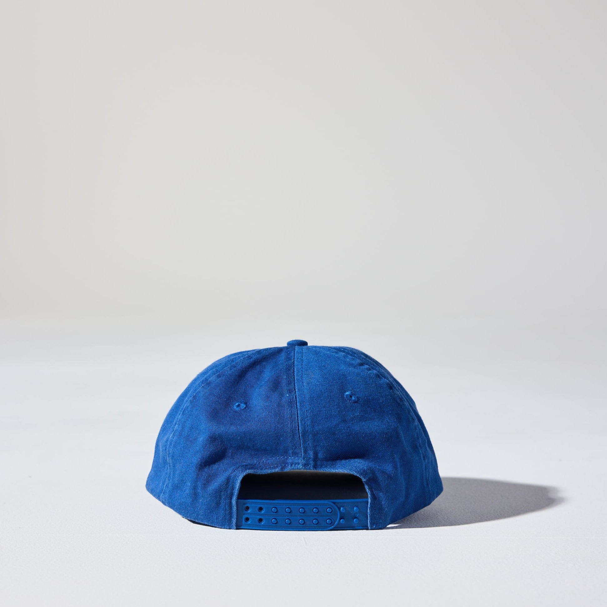 A blue 6 panel snapback cap made of recycled cotton twill, displayed against a neutral background. Retro-style Monday Snap Cap with soft unstructured peak.