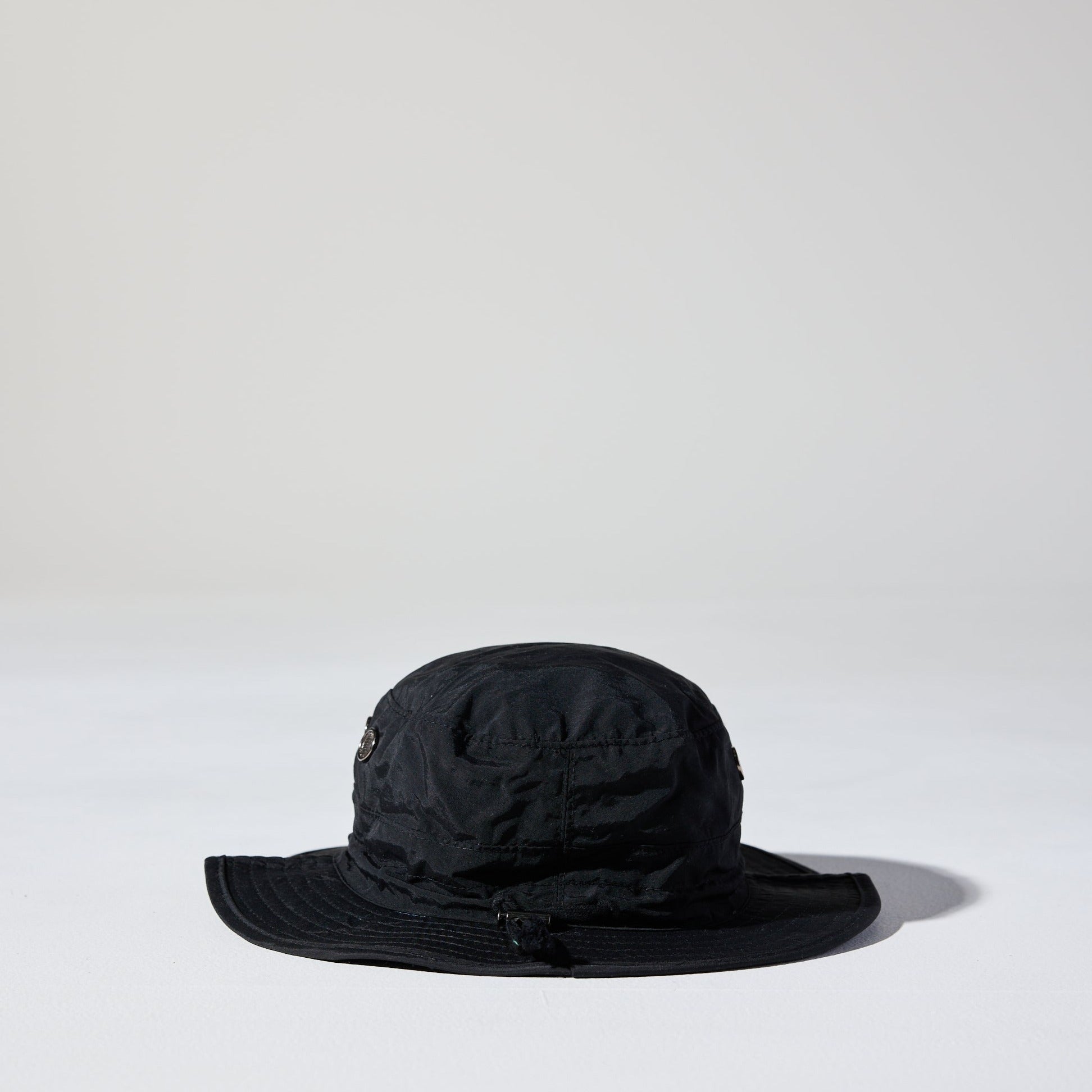 A black Saturday Nylon Bucket Hat by House of Peaks with wide brim, adjustable chin strap, hidden pocket – lightweight and water-resistant, 58cm crown size.