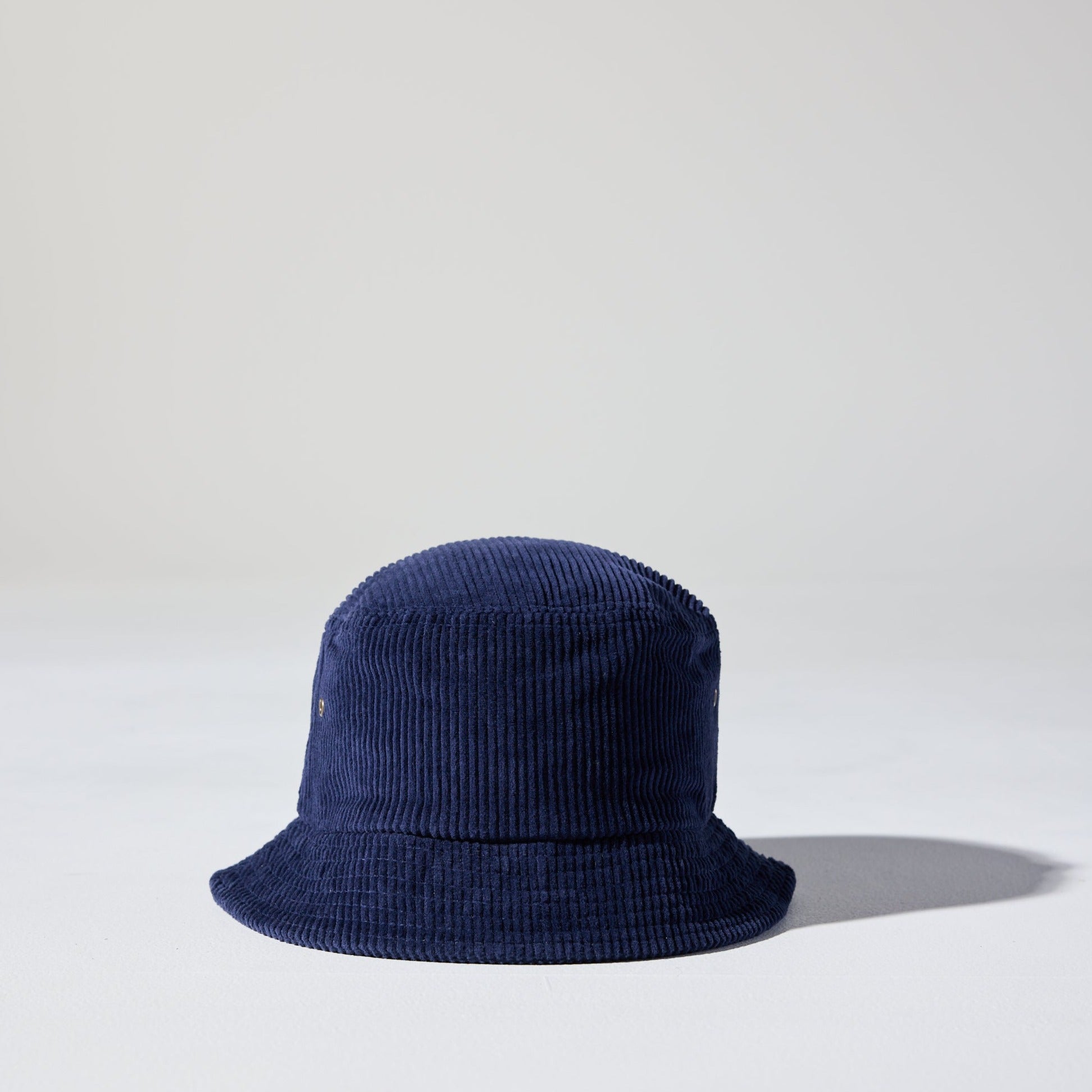 A navy blue Sunday Corduroy Bucket Hat against a white background – lightweight, floppy style with 59cm circumference, classic wide brim, unstructured fit. House of Peaks hats are the best blank hats in Australia.