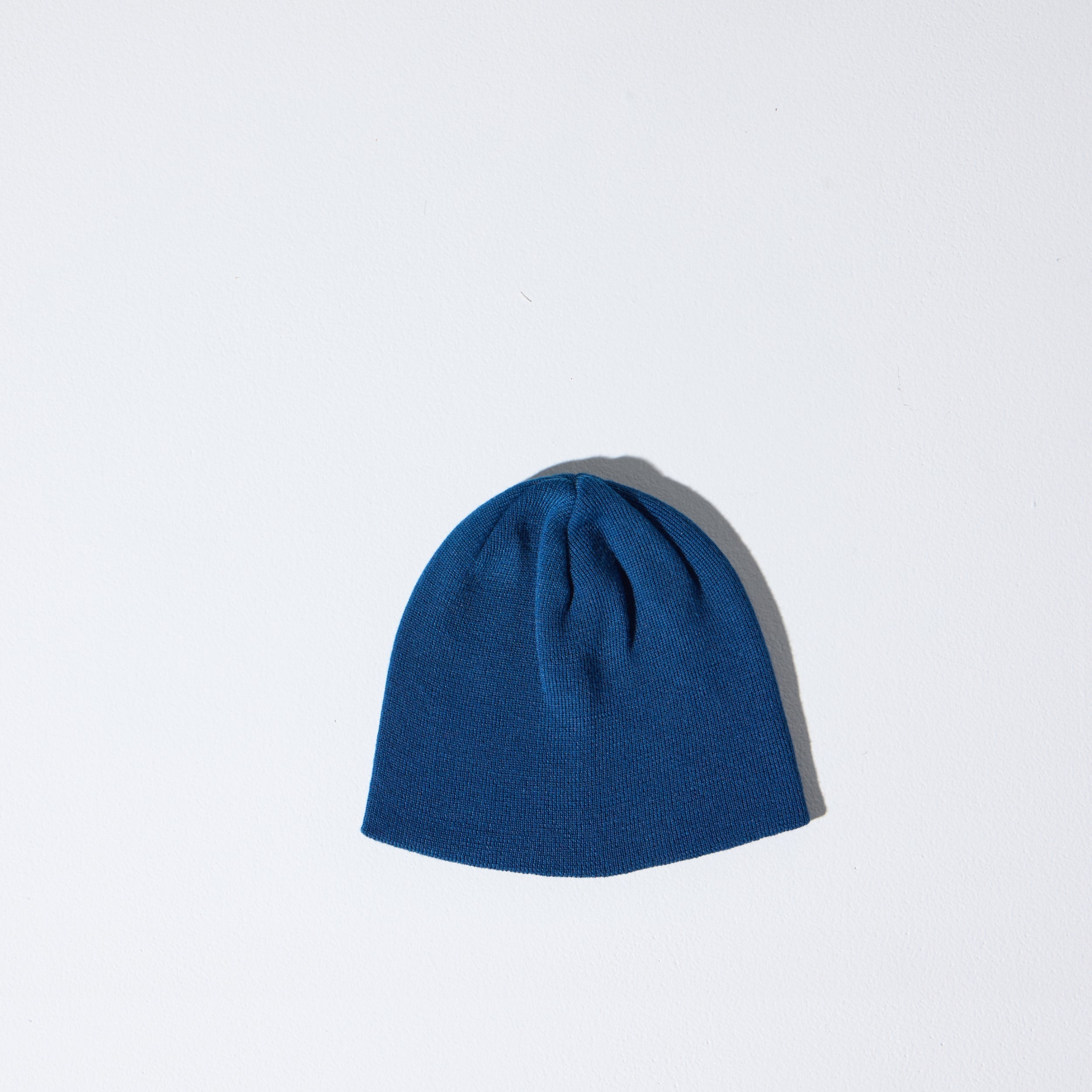 A blue Skully Beanie by House of Peaks on a white background - a 100% Polylana skull cap fit, no cuff, 90’s retro-inspired sustainable knit hat.