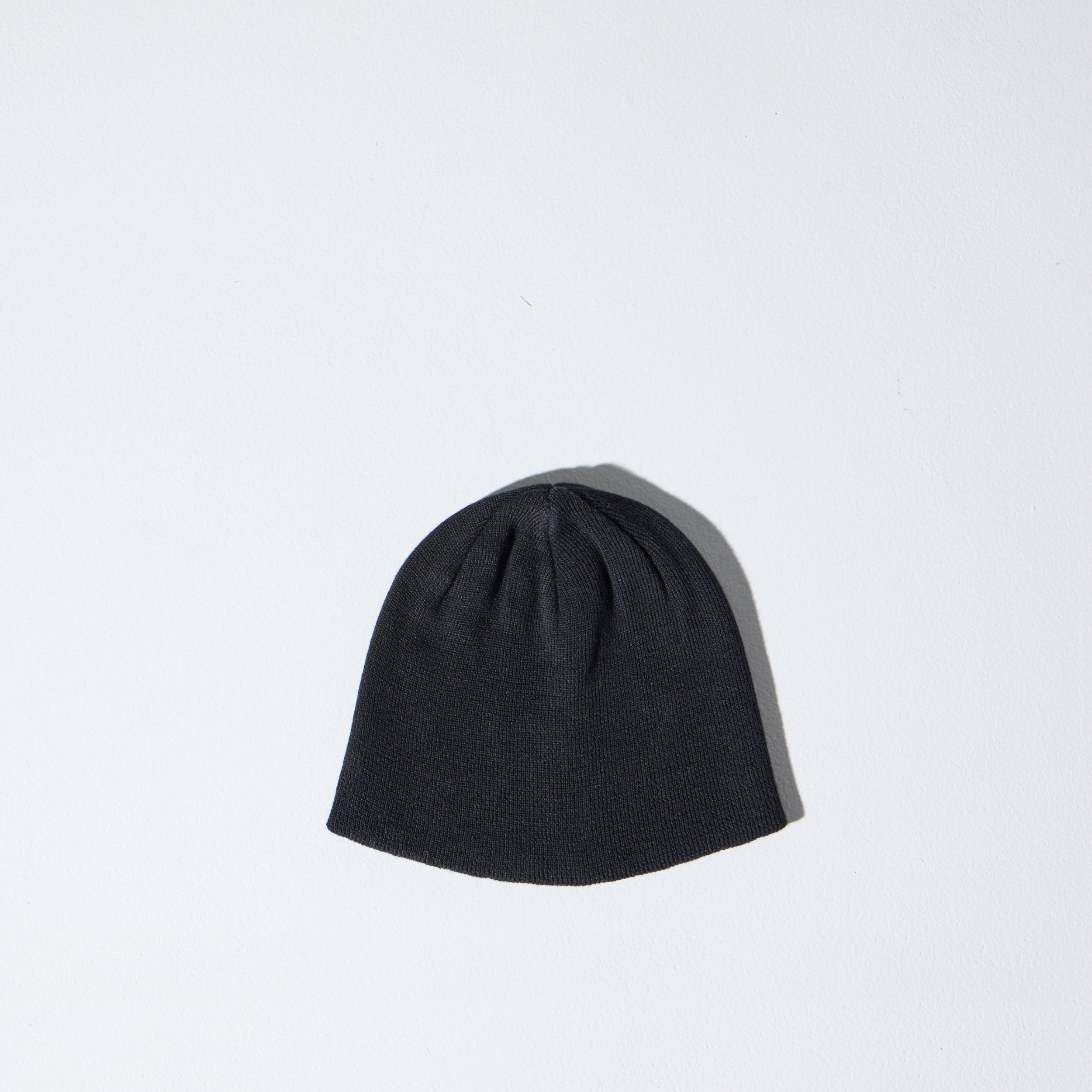 A black Skully Beanie by House of Peaks on a white background - a 100% Polylana skull cap fit, no cuff, 90’s retro-inspired sustainable knit hat.
